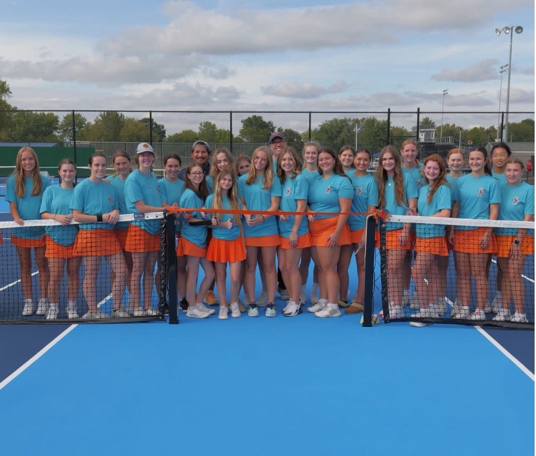 The RHS girls' tennis team smiles before cutting the ceremonial ribbon.